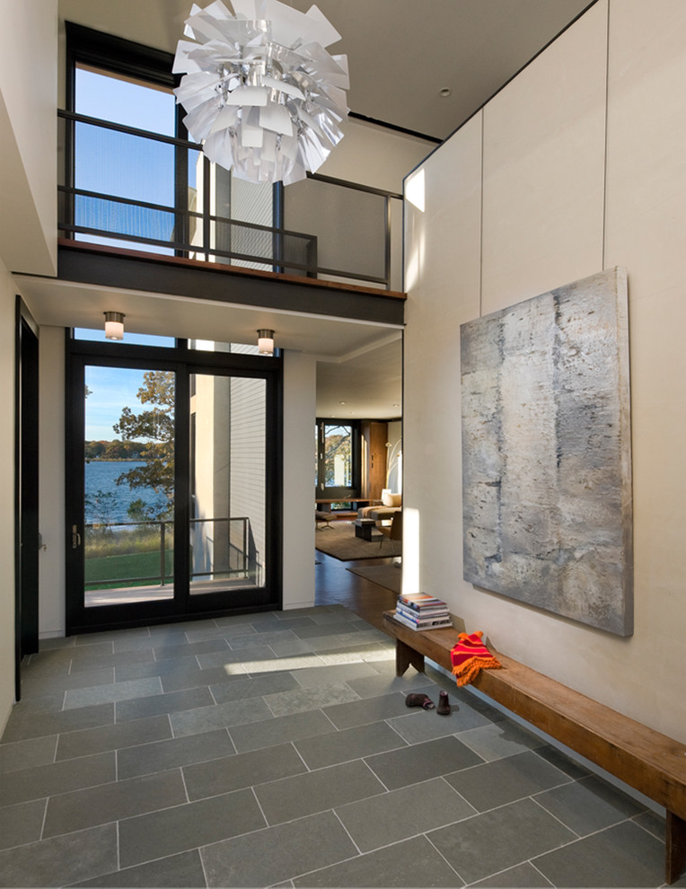 This is an example of a modern entryway in New York with beige walls, a glass front door, slate floors and grey floor.