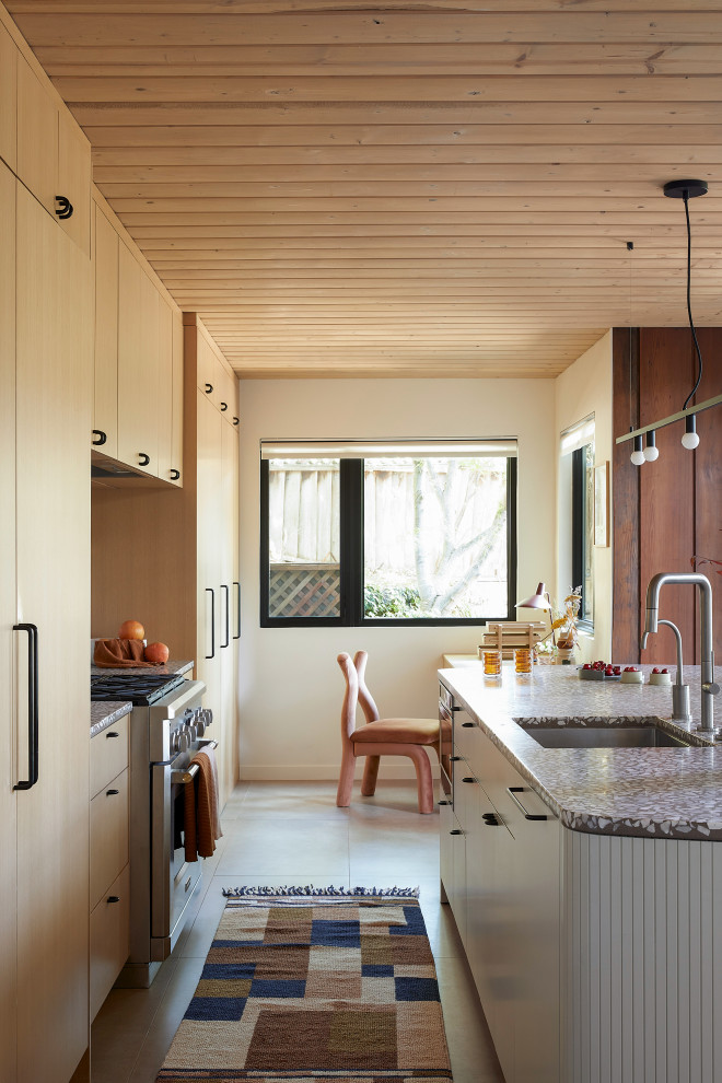 This is an example of a mid-sized midcentury single-wall open plan kitchen in San Francisco with an undermount sink, flat-panel cabinets, light wood cabinets, terrazzo benchtops, grey splashback, cement tile splashback, panelled appliances, porcelain floors, with island, beige floor, grey benchtop and wood.