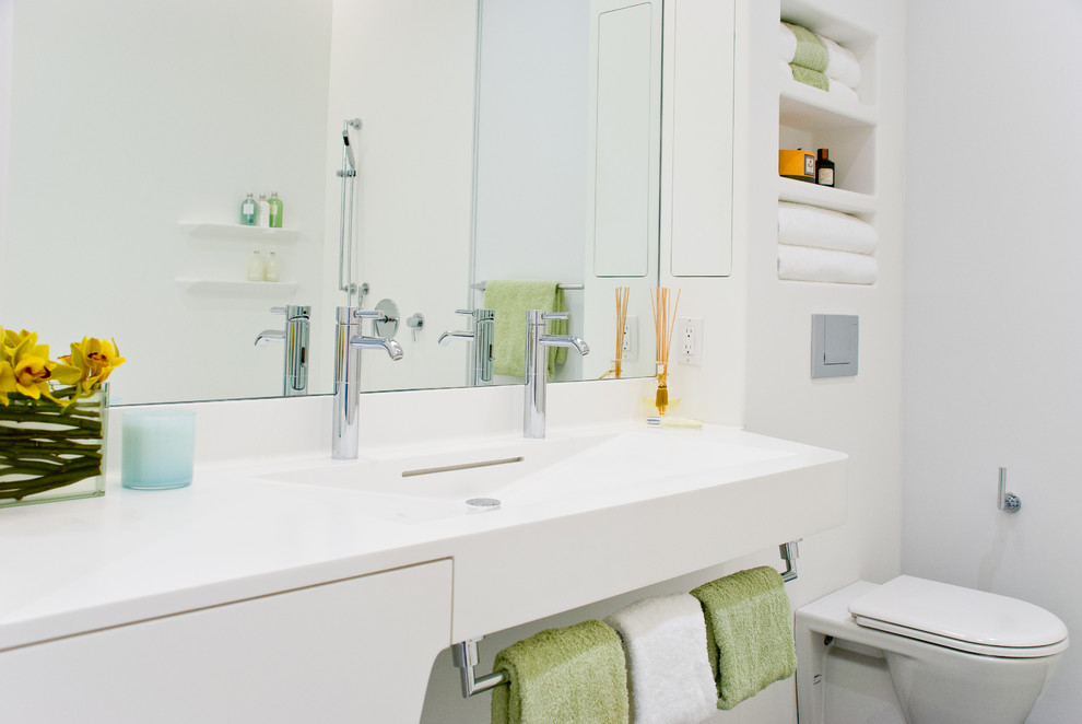 Photo of a contemporary bathroom in New York with solid surface benchtops and a wall-mount toilet.