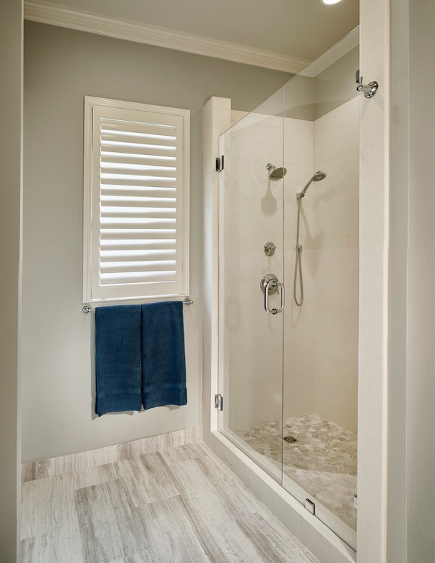 Photo of a mid-sized contemporary bathroom in Dallas with flat-panel cabinets, light wood cabinets, a corner shower, a two-piece toilet, white tile, stone tile, grey walls, limestone floors and an undermount sink.