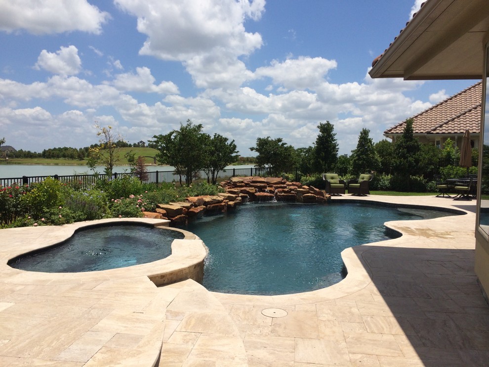 Photo of a traditional backyard custom-shaped natural pool in Houston with natural stone pavers.