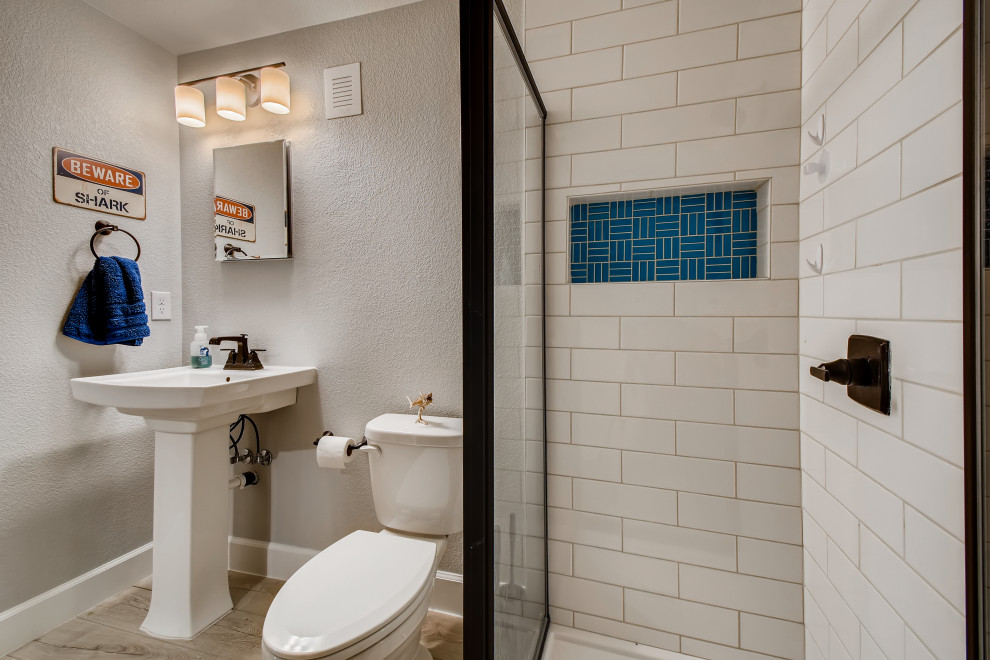 Inredning av ett modernt mellanstort badrum med dusch, med en hörndusch, vit kakel, keramikplattor, vita väggar, vinylgolv, ett piedestal handfat, grått golv och dusch med gångjärnsdörr