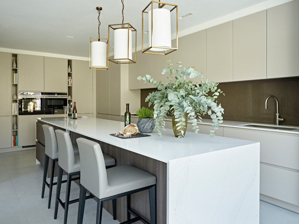 Design ideas for a large contemporary l-shaped kitchen in London with an undermount sink, flat-panel cabinets, beige cabinets, marble benchtops, brown splashback, stainless steel appliances, with island, grey floor and white benchtop.