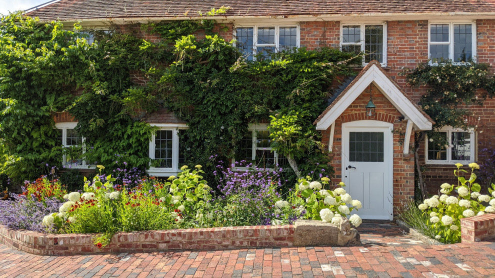 Пример оригинального дизайна: большой солнечный, летний регулярный сад на заднем дворе в классическом стиле с подпорной стенкой, хорошей освещенностью, покрытием из гальки и с каменным забором