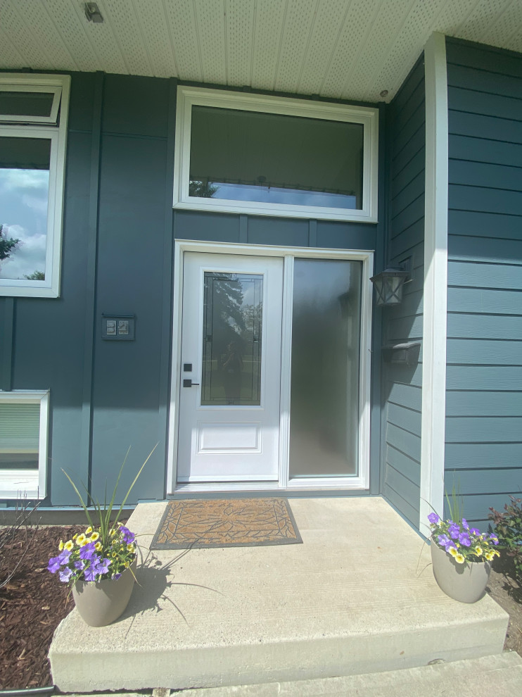 Photo of a traditional front door in Calgary with blue walls, concrete flooring, a single front door and a white front door.