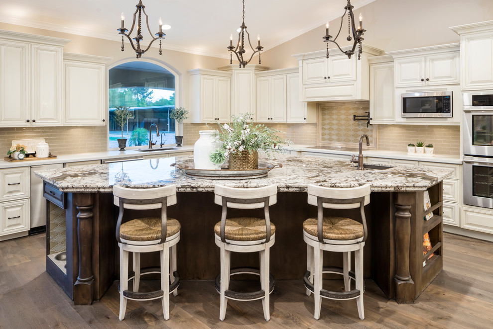 Example of a large transitional l-shaped medium tone wood floor and brown floor eat-in kitchen design in Phoenix with an undermount sink, raised-panel cabinets, beige backsplash, glass tile backsplash, stainless steel appliances, an island, beige cabinets and quartz countertops