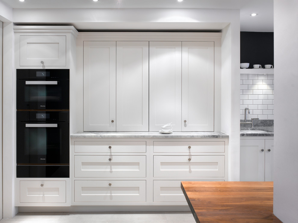 Inspiration for a large contemporary kitchen pantry in London with recessed-panel cabinets and grey cabinets.
