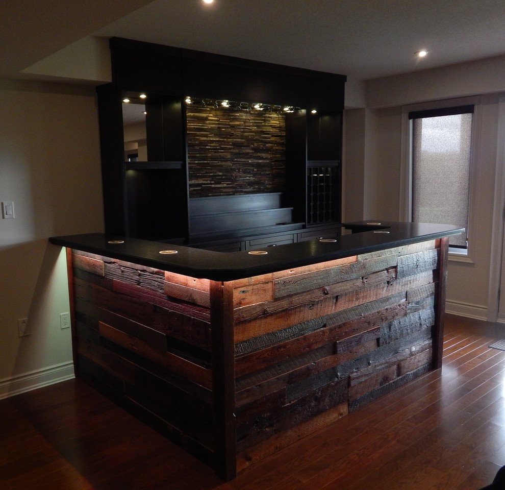 Inspiration for a small country galley home bar in Toronto with solid surface benchtops, brown splashback, stone tile splashback, dark hardwood floors and brown floor.
