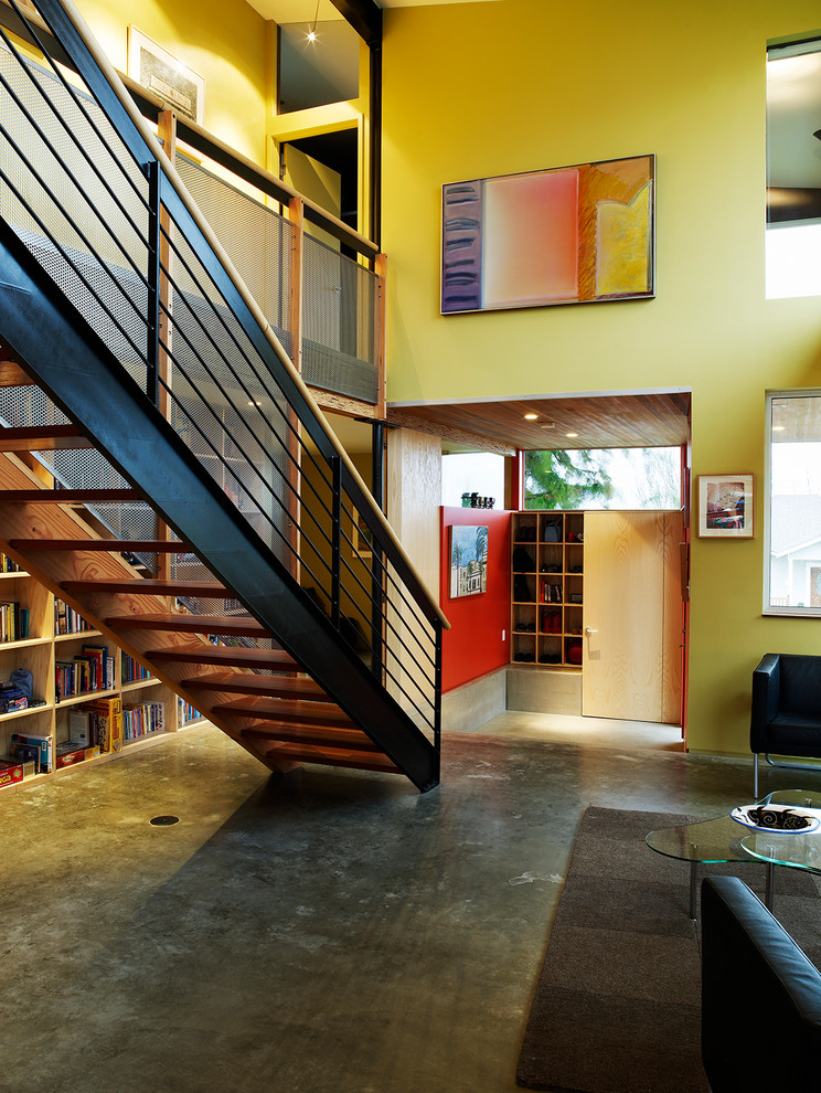Photo of a small industrial open concept living room in Seattle with yellow walls and concrete floors.