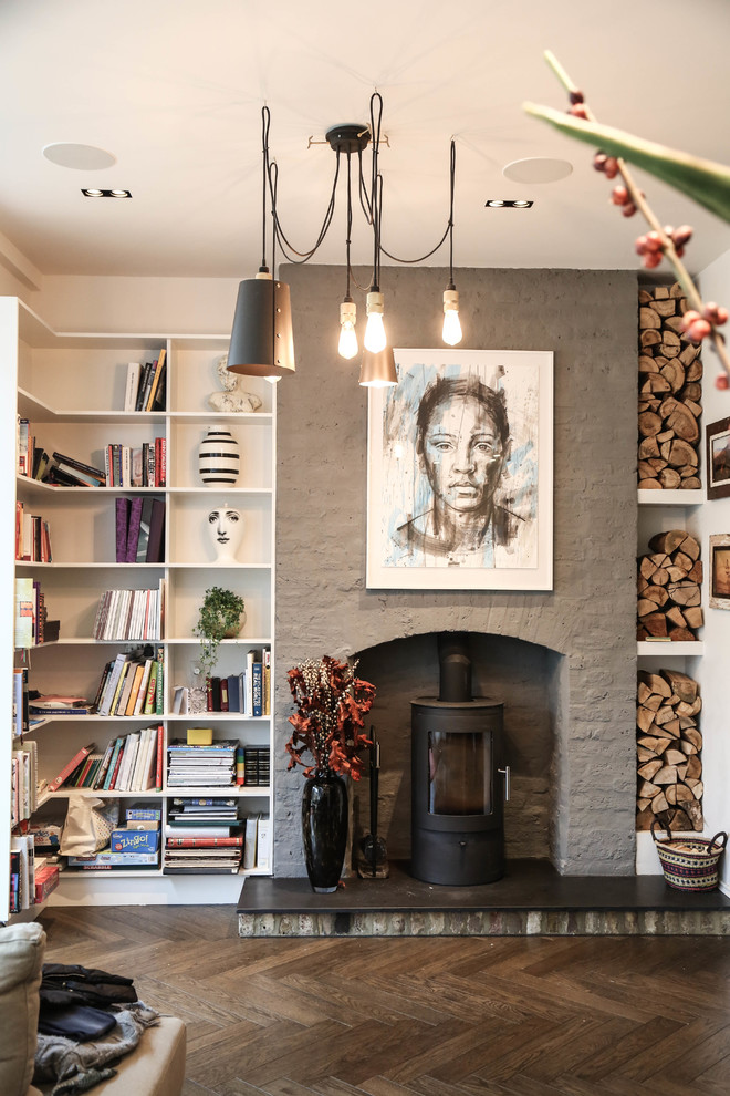 Inspiration for a large contemporary open concept living room in London with a library, grey walls, dark hardwood floors and a wood stove.