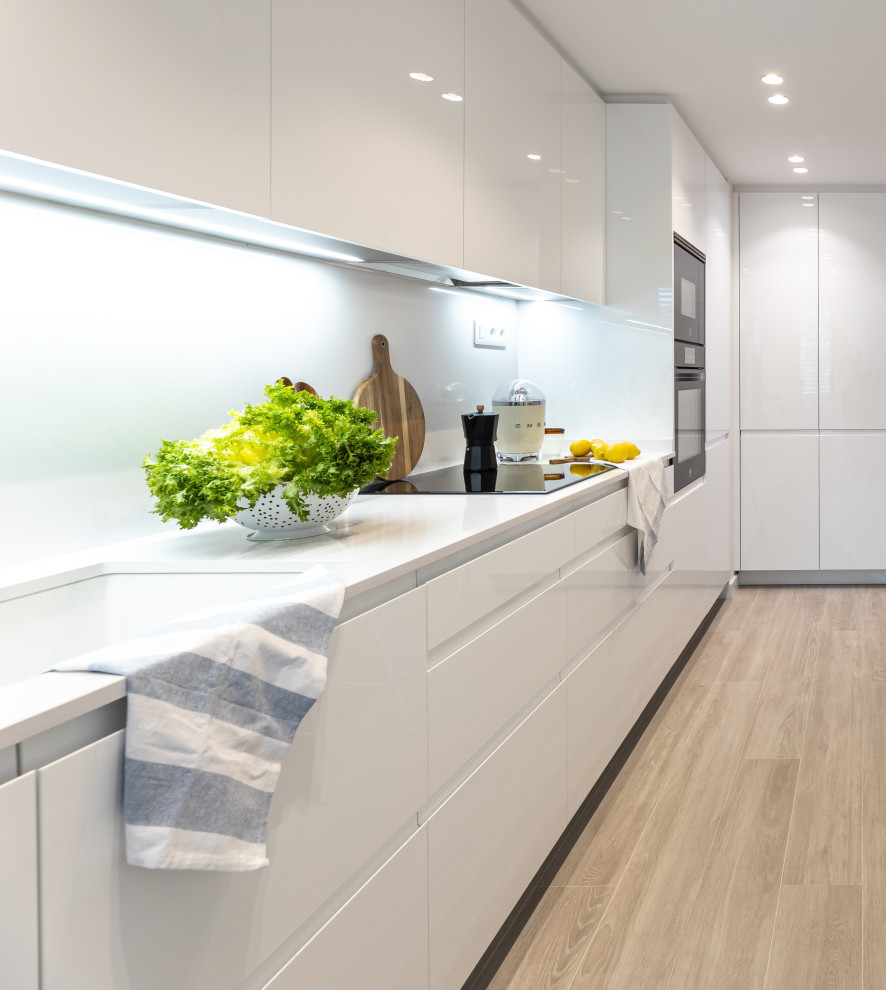 Photo of a medium sized modern l-shaped enclosed kitchen in Barcelona with a submerged sink, white cabinets, engineered stone countertops, white splashback, engineered quartz splashback, black appliances, ceramic flooring, no island, beige floors and white worktops.