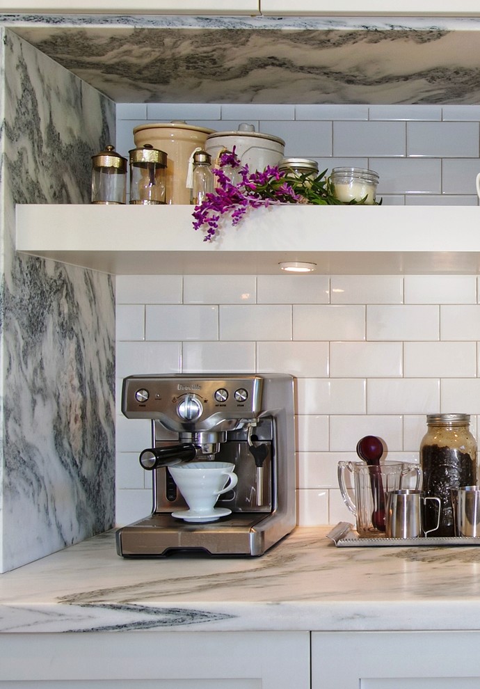 Mid-sized transitional u-shaped travertine floor and beige floor open concept kitchen photo in San Diego with a farmhouse sink, flat-panel cabinets, white cabinets, marble countertops, white backsplash, subway tile backsplash, stainless steel appliances and an island