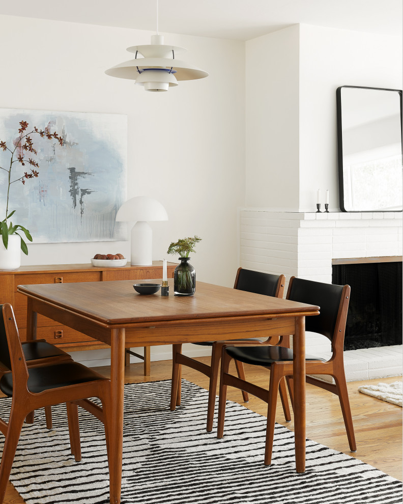 Immagine di una sala da pranzo minimalista di medie dimensioni con pareti bianche, pavimento in legno massello medio, camino classico, cornice del camino in mattoni e pavimento marrone