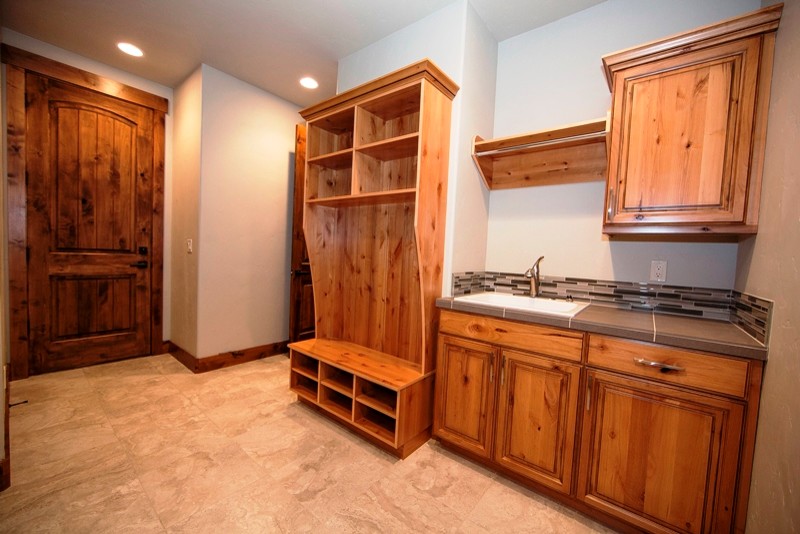 Mid-sized country single-wall utility room in Seattle with a drop-in sink, beaded inset cabinets, medium wood cabinets, tile benchtops, white walls and porcelain floors.