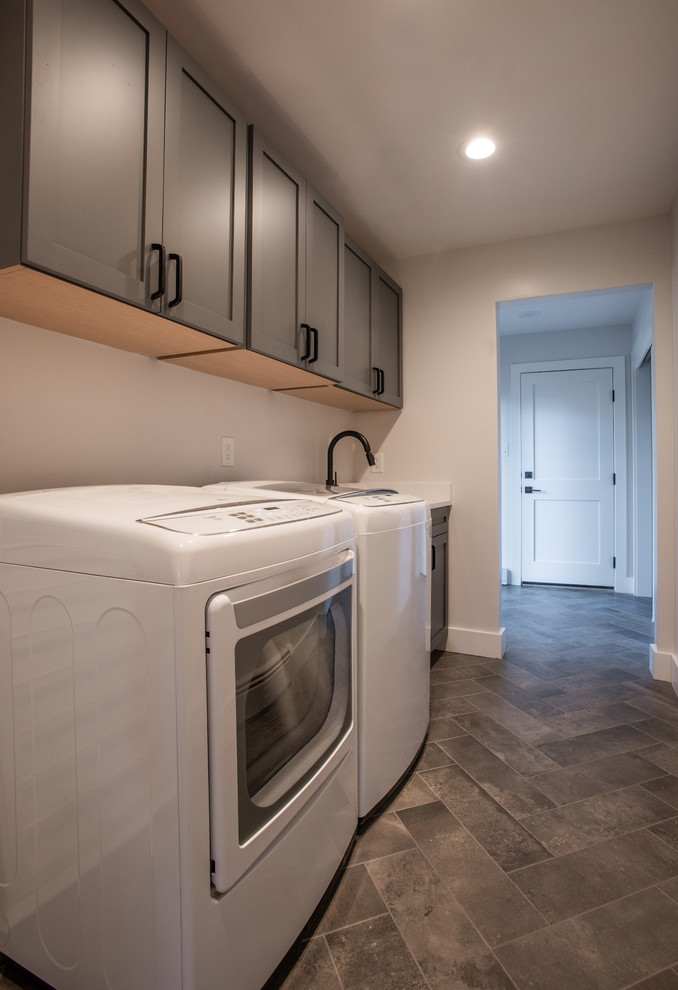 Photo of a mid-sized contemporary single-wall utility room in Denver with an undermount sink, shaker cabinets, black cabinets, quartz benchtops, beige walls, a side-by-side washer and dryer and white benchtop.