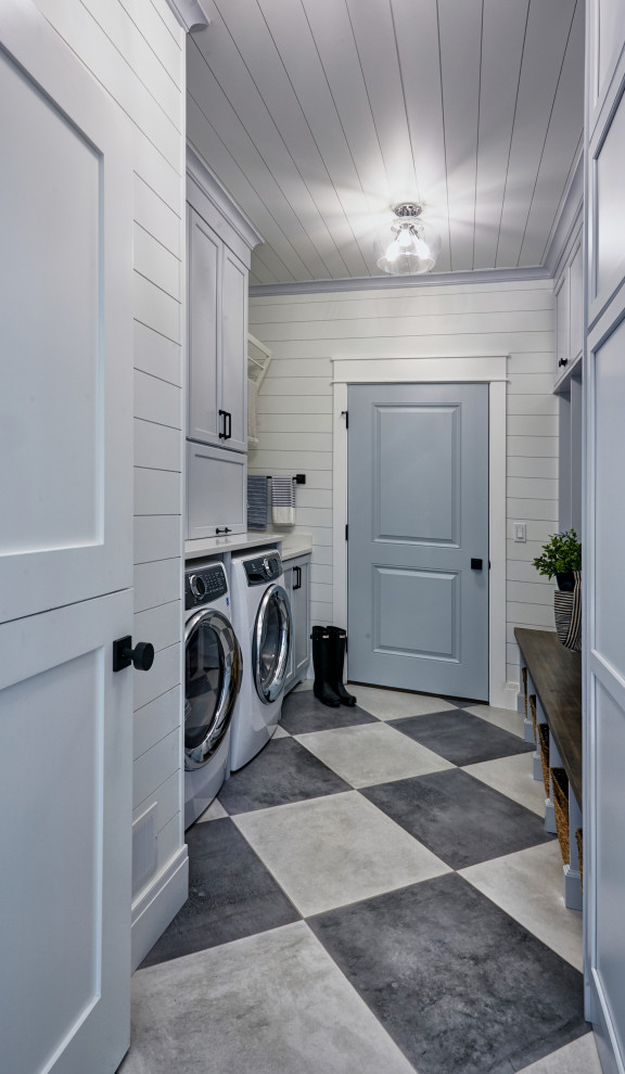 Photo of a mid-sized beach style galley utility room in Other with an undermount sink, flat-panel cabinets, blue cabinets, quartzite benchtops, white walls, ceramic floors, a concealed washer and dryer, blue floor and white benchtop.