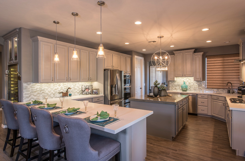 Inspiration for a large transitional open plan kitchen in Phoenix with raised-panel cabinets, grey cabinets, solid surface benchtops, stainless steel appliances, ceramic floors and multiple islands.