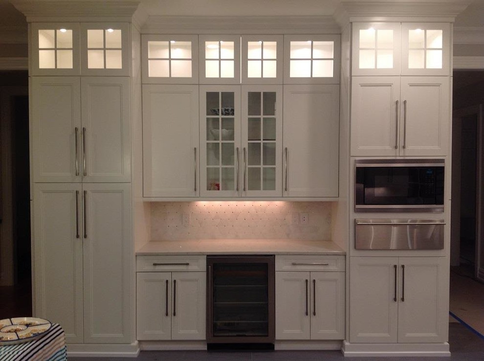 Mid-sized transitional u-shaped concrete floor and gray floor eat-in kitchen photo in New York with an undermount sink, recessed-panel cabinets, white cabinets, marble countertops, white backsplash, porcelain backsplash, stainless steel appliances and an island