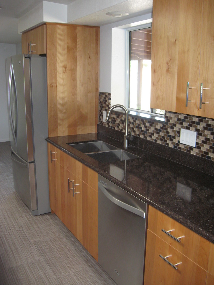 Open concept kitchen - mid-sized transitional galley porcelain tile and beige floor open concept kitchen idea in Phoenix with a double-bowl sink, flat-panel cabinets, light wood cabinets, granite countertops, brown backsplash, glass tile backsplash, stainless steel appliances and an island