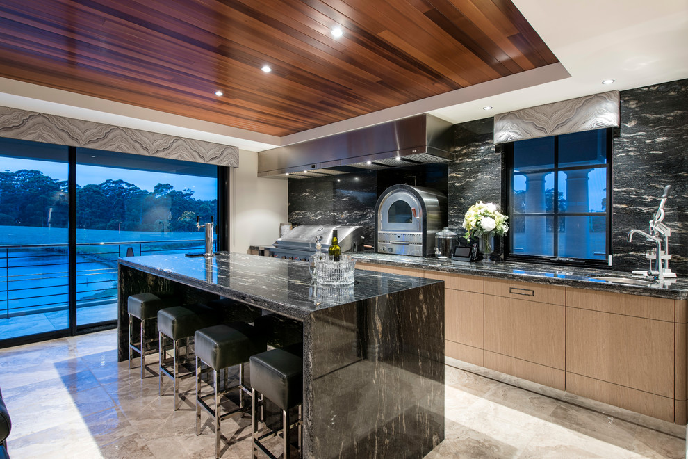 Photo of a contemporary galley open plan kitchen in Perth with flat-panel cabinets, light wood cabinets, black splashback, stone slab splashback, stainless steel appliances and with island.