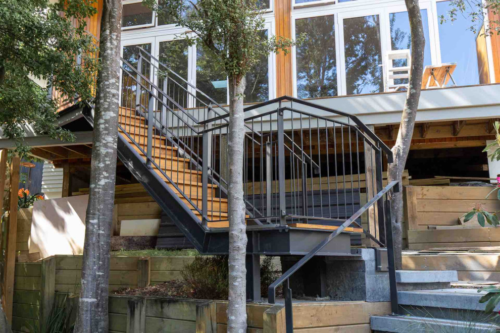 Example of a mid-sized urban wooden l-shaped metal railing staircase design in Auckland with wooden risers