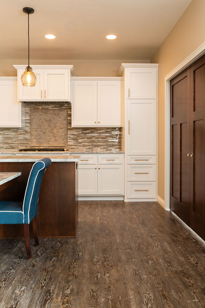 Kitchen - large transitional vinyl floor and brown floor kitchen idea with an undermount sink, white cabinets, granite countertops, metallic backsplash, glass tile backsplash, stainless steel appliances, recessed-panel cabinets and an island