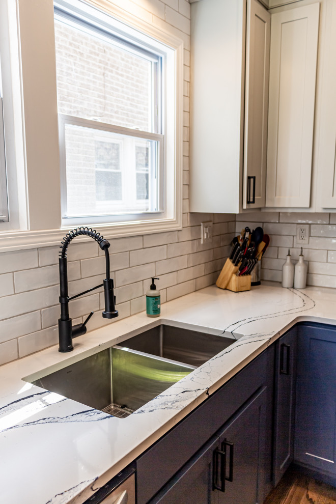 Inspiration for a small transitional u-shaped medium tone wood floor and brown floor eat-in kitchen remodel in St Louis with an undermount sink, shaker cabinets, blue cabinets, quartz countertops, white backsplash, subway tile backsplash, stainless steel appliances and white countertops