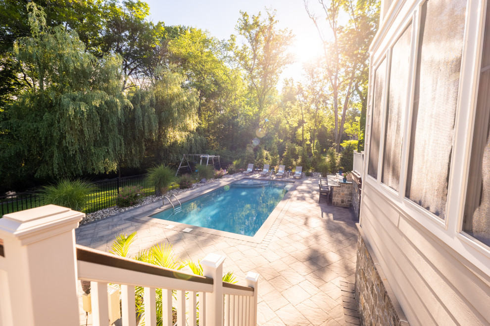 Imagen de piscina alargada contemporánea grande rectangular en patio trasero con paisajismo de piscina y adoquines de hormigón