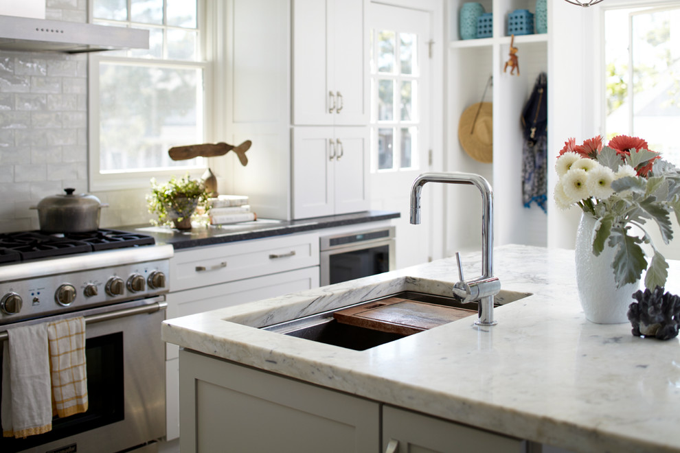 Inspiration for a large beach style u-shaped eat-in kitchen in New York with an undermount sink, shaker cabinets, white cabinets, granite benchtops, white splashback, subway tile splashback, stainless steel appliances, limestone floors and with island.