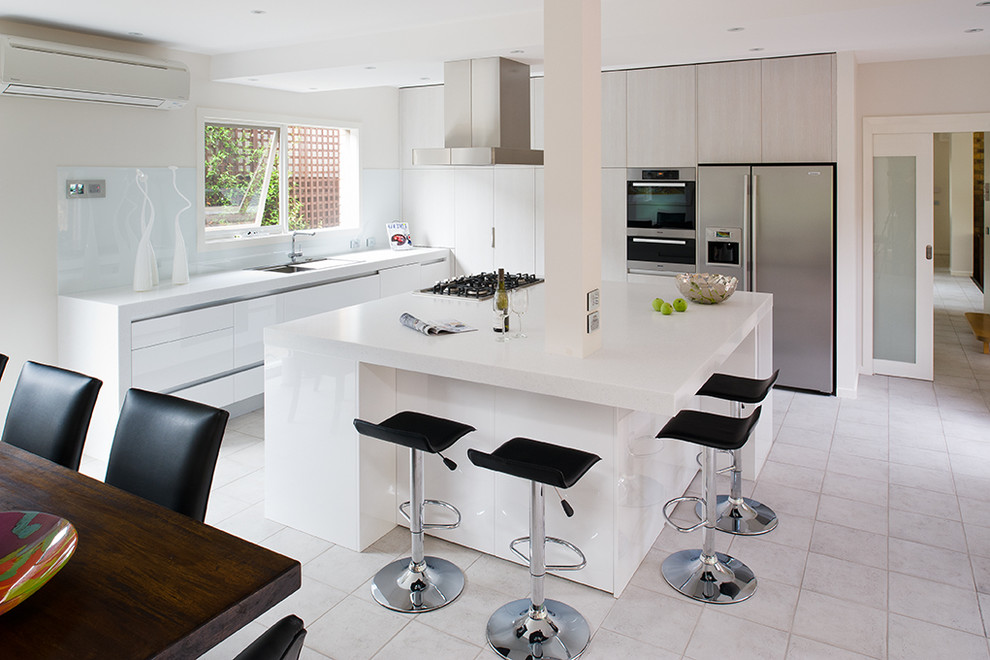 Photo of a mid-sized modern galley kitchen in Melbourne with an undermount sink, flat-panel cabinets, white cabinets, solid surface benchtops, stainless steel appliances, ceramic floors and with island.