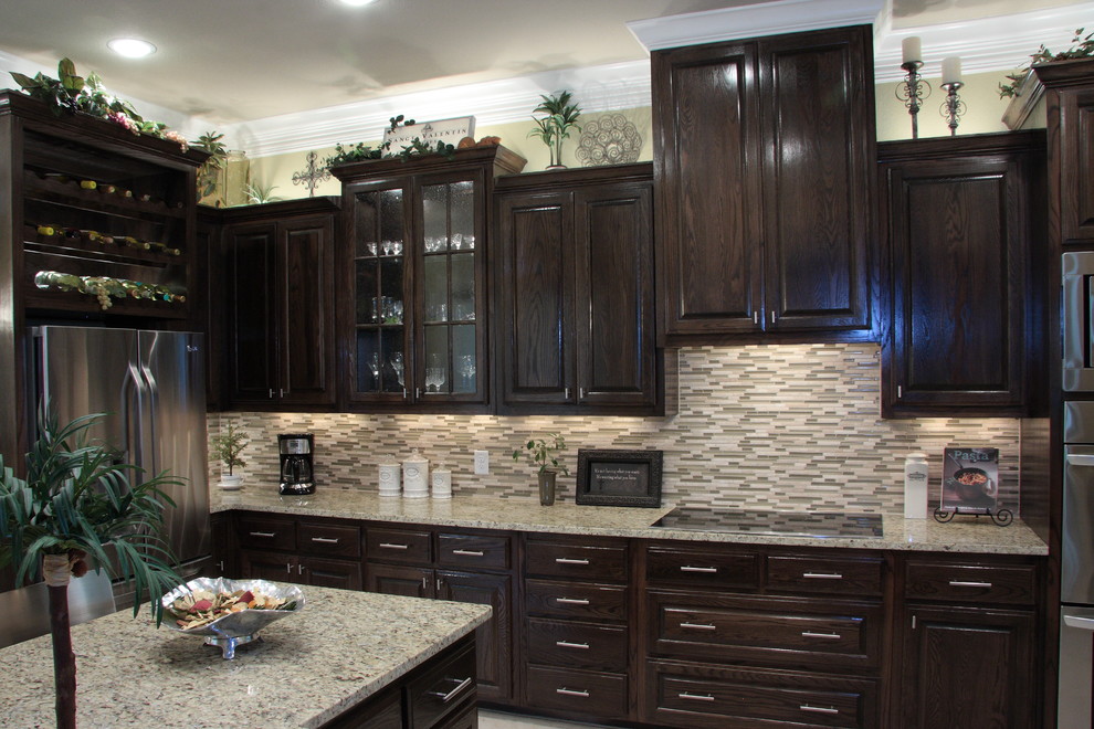 Photo of a mediterranean single-wall open plan kitchen in Austin with raised-panel cabinets, dark wood cabinets, granite benchtops, multi-coloured splashback, glass tile splashback, stainless steel appliances, linoleum floors and a peninsula.