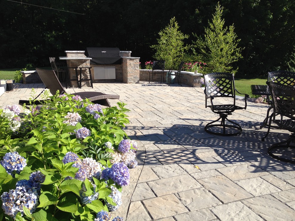 Photo of an expansive traditional backyard patio in Portland Maine with an outdoor kitchen, concrete pavers and no cover.