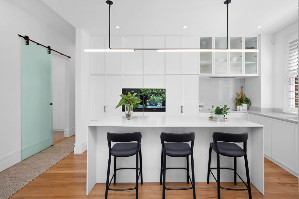 This is an example of a large transitional kitchen in Sydney with quartz benchtops and with island.