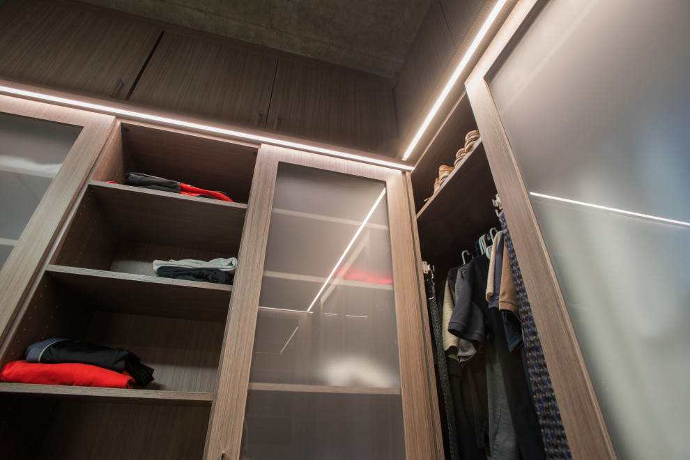 Design ideas for a mid-sized modern men's walk-in wardrobe in Denver with flat-panel cabinets, medium wood cabinets, ceramic floors, grey floor and vaulted.