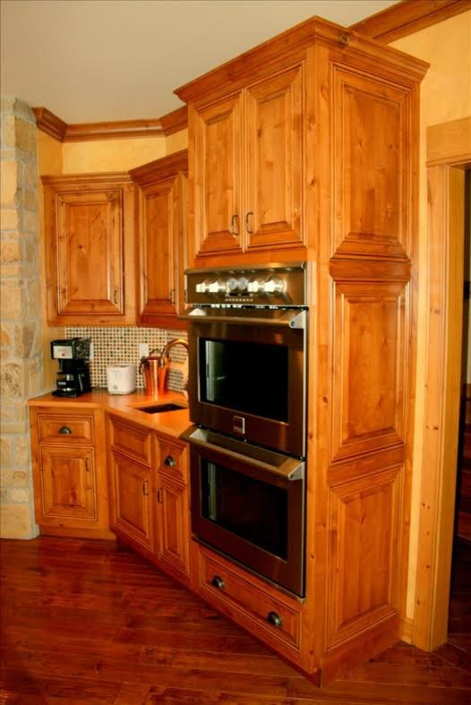Inspiration for a transitional dark wood floor enclosed kitchen remodel with a farmhouse sink, medium tone wood cabinets, stainless steel appliances, raised-panel cabinets and quartz countertops