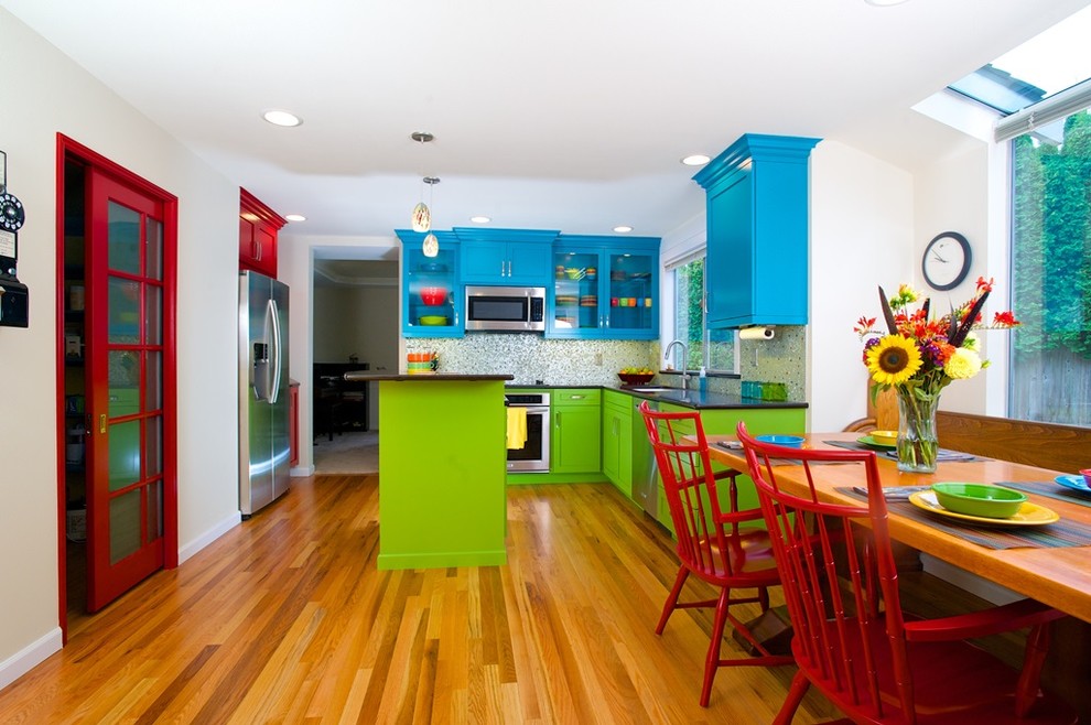 Kitchen pantry - mid-sized eclectic u-shaped medium tone wood floor and brown floor kitchen pantry idea in Seattle with an undermount sink, recessed-panel cabinets, red cabinets, quartz countertops, multicolored backsplash, glass tile backsplash, stainless steel appliances and an island