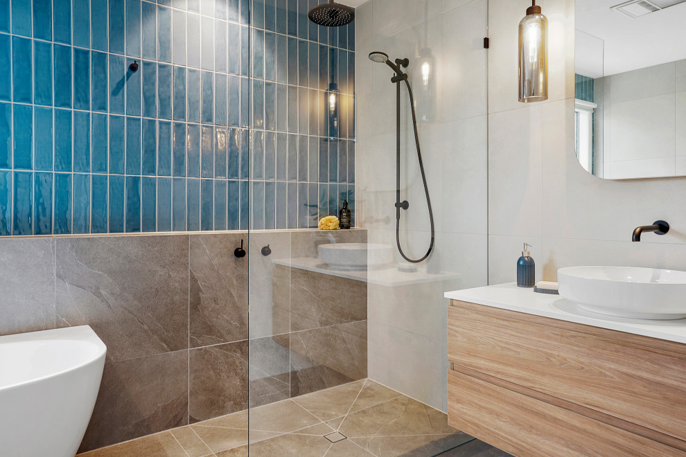 Design ideas for a mid-sized contemporary bathroom in Melbourne with flat-panel cabinets, light wood cabinets, a curbless shower, blue tile, ceramic tile, blue walls, porcelain floors, a vessel sink, engineered quartz benchtops, grey floor, white benchtops, a single vanity and a floating vanity.