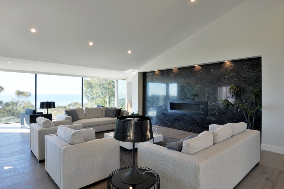 Inspiration for an expansive modern enclosed living room in San Diego with a home bar, white walls, light hardwood floors, a ribbon fireplace, a stone fireplace surround and no tv.
