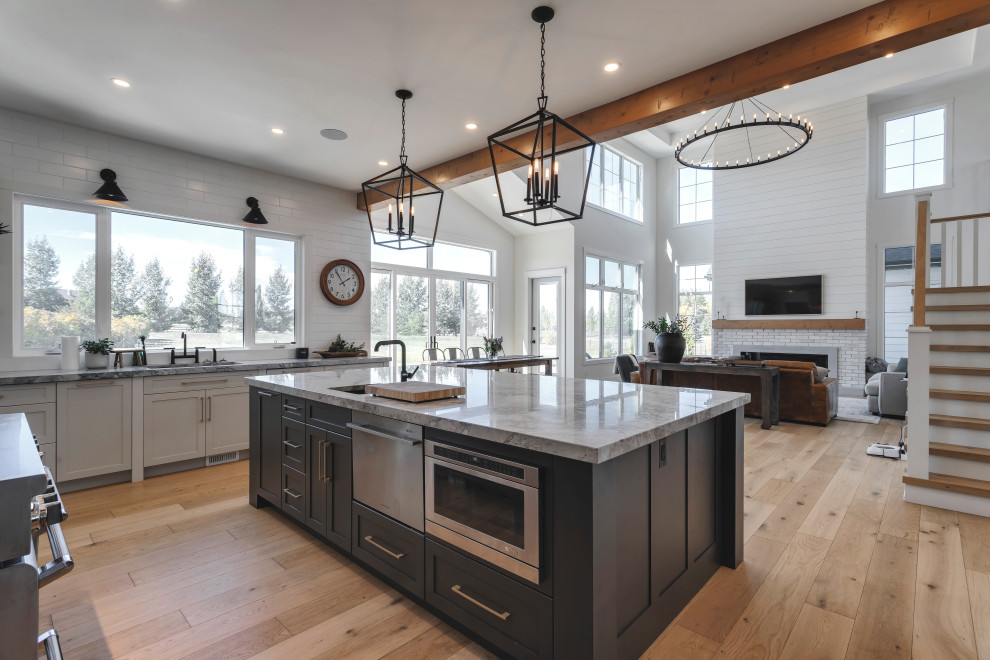 Large modern u-shaped eat-in kitchen in Calgary with an undermount sink, recessed-panel cabinets, white cabinets, marble benchtops, white splashback, subway tile splashback, stainless steel appliances, light hardwood floors, with island, white benchtop and exposed beam.