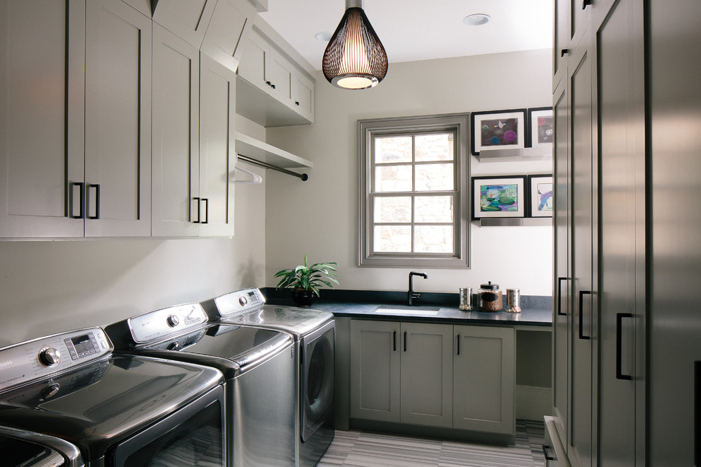 This is an example of a modern u-shaped laundry room in Atlanta with an undermount sink, grey cabinets, grey walls, porcelain floors and shaker cabinets.