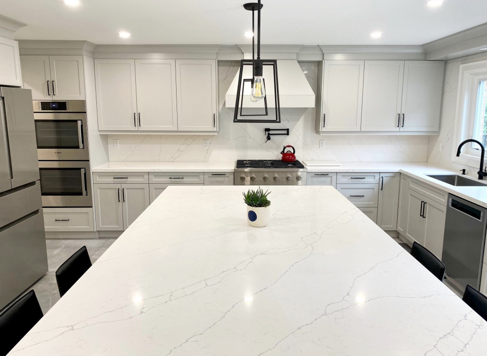 Open concept kitchen - mid-sized transitional l-shaped porcelain tile open concept kitchen idea in Toronto with an undermount sink, shaker cabinets, gray cabinets, quartz countertops, white backsplash, quartz backsplash, stainless steel appliances, an island and white countertops
