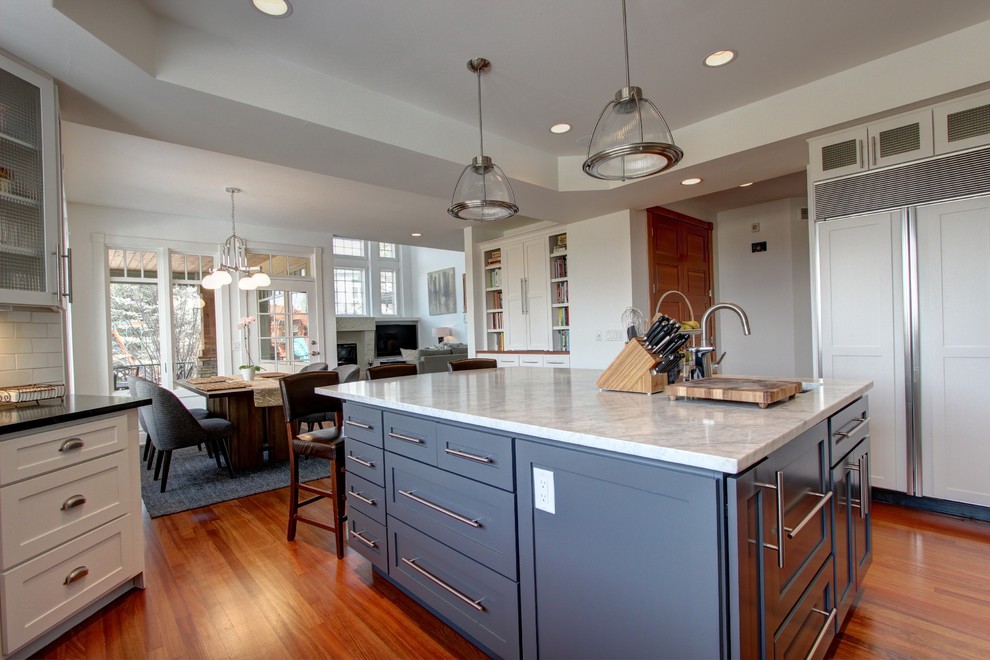 Inspiration for a large transitional l-shaped eat-in kitchen in Denver with an undermount sink, glass-front cabinets, white cabinets, soapstone benchtops, white splashback, subway tile splashback, panelled appliances, dark hardwood floors and with island.