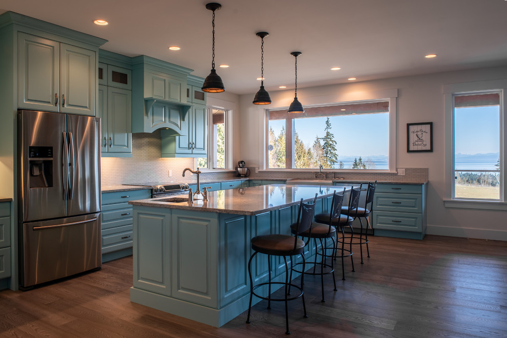 Inspiration for a large country l-shaped open plan kitchen in Vancouver with turquoise cabinets, marble benchtops, white splashback, mosaic tile splashback, with island, grey benchtop, a farmhouse sink, raised-panel cabinets, stainless steel appliances, dark hardwood floors and brown floor.