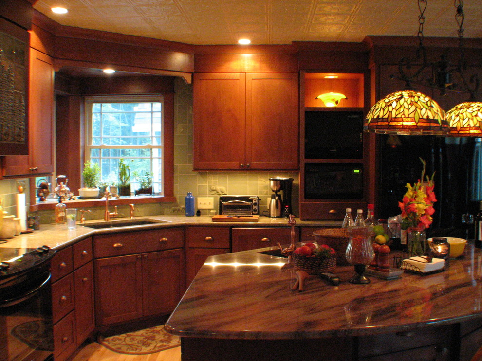 Kitchen - small traditional l-shaped light wood floor kitchen idea with an undermount sink, shaker cabinets, medium tone wood cabinets, granite countertops, green backsplash, mosaic tile backsplash, black appliances and an island