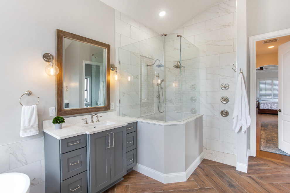 Klassisk inredning av ett stort vit vitt en-suite badrum, med skåp i shakerstil, grå skåp, ett fristående badkar, en hörndusch, grå väggar, ett undermonterad handfat, bänkskiva i kvarts, brunt golv och med dusch som är öppen