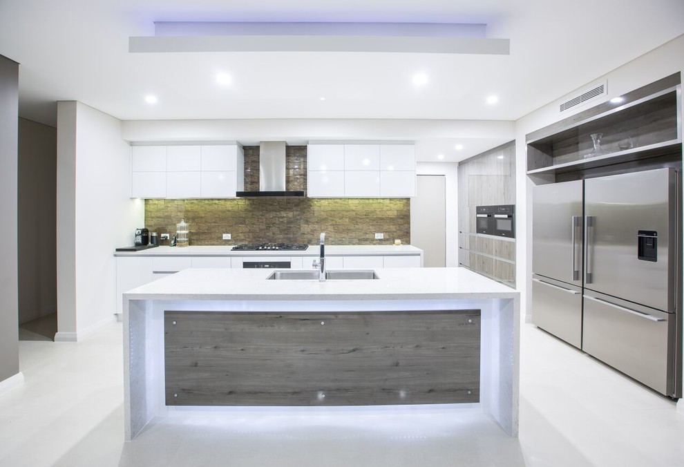 Inspiration for a modern l-shaped open plan kitchen in Perth with an undermount sink, solid surface benchtops, multi-coloured splashback, stone tile splashback, black appliances, ceramic floors, with island, white floor and white benchtop.