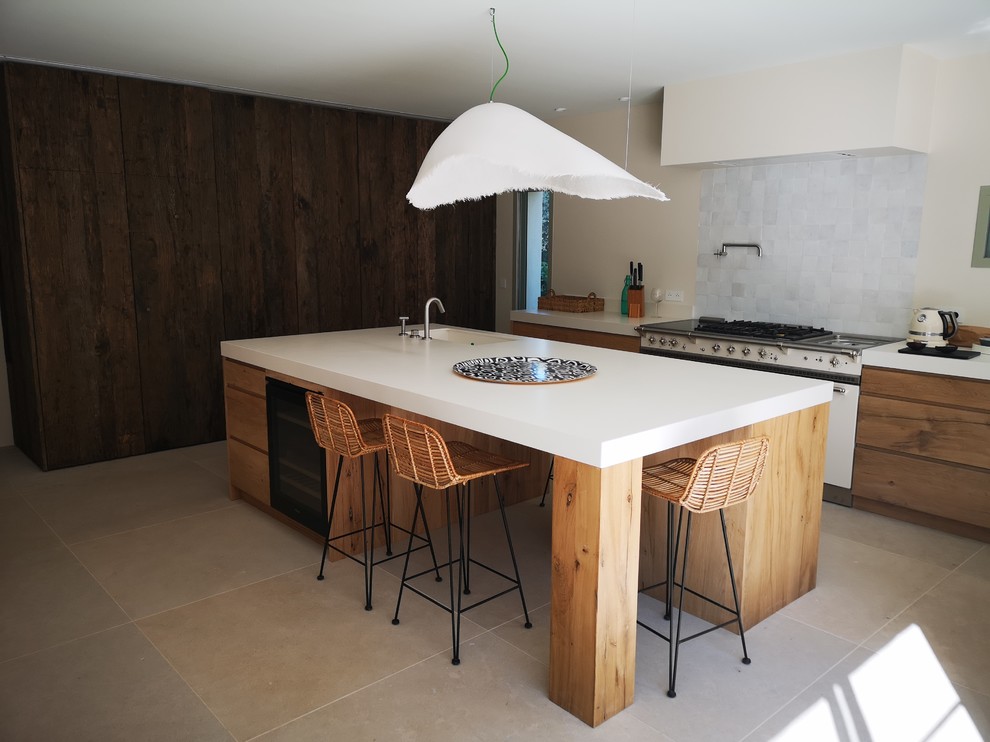 Large contemporary l-shaped open plan kitchen in Other with an undermount sink, flat-panel cabinets, light wood cabinets, tile benchtops, white splashback, white appliances, travertine floors, with island, beige floor and beige benchtop.