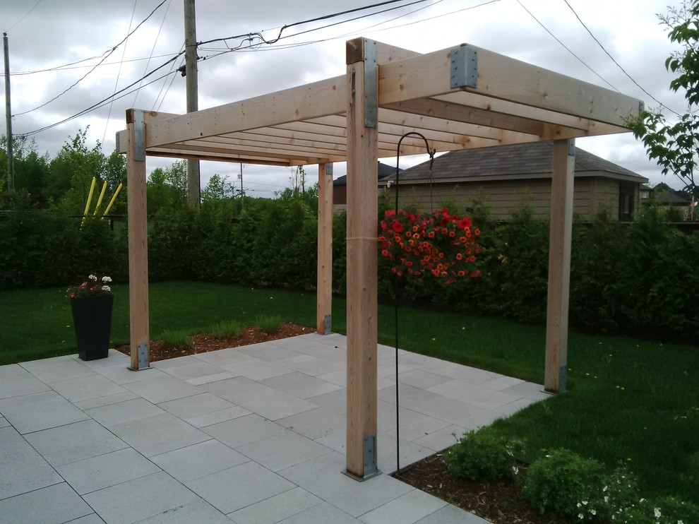 This is an example of a small modern backyard deck in Montreal with a vertical garden and a pergola.