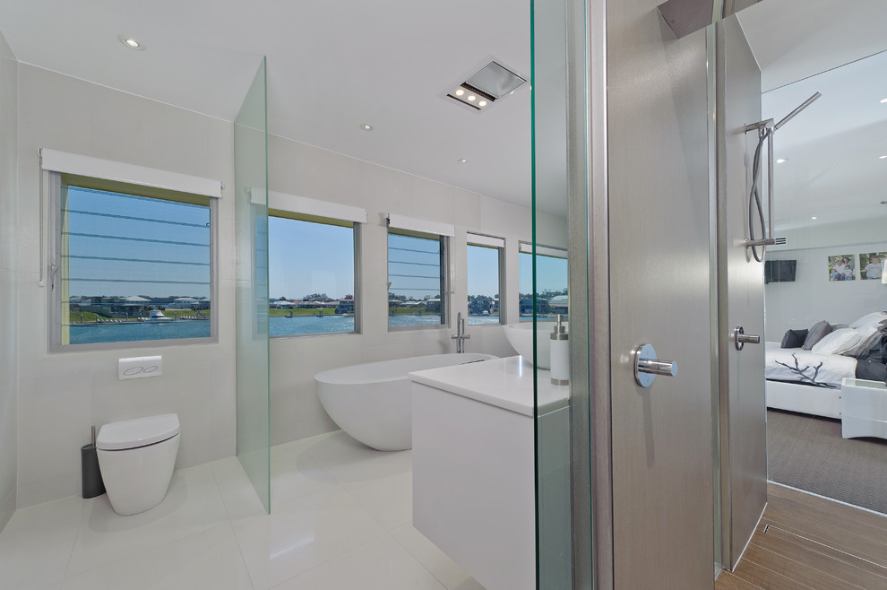 Contemporary bathroom in Central Coast with a vessel sink, flat-panel cabinets, white cabinets, solid surface benchtops, a freestanding tub, an open shower, a one-piece toilet, multi-coloured tile and porcelain tile.