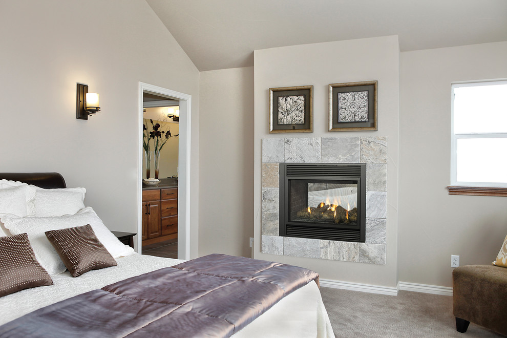 Photo of a mid-sized traditional master bedroom in Seattle with beige walls, carpet, a hanging fireplace, a tile fireplace surround and grey floor.